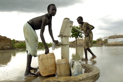 Displaced children fetch water using a submerged hand pump following flooding in the villages caused by extremely heavy early rains villages that displaced thousands of residents.