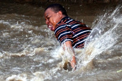 A man struggles to wade through a flooded road (file photo).