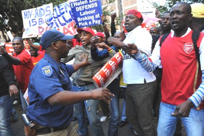 A police officer tries to control a tense situation between an angry Cosatu crowd and Democratic Alliance supporters in Johannesburg, South Africa.