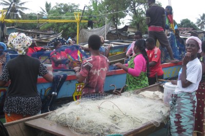 Market women help fishermen prepare their nets for the night time fishing expedition (file photo).