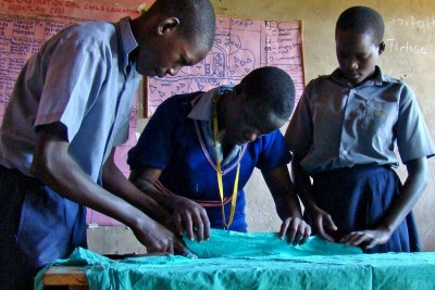 Pupils take measurements of a cotton cloth to be used to make sanitary pads in Uganda.