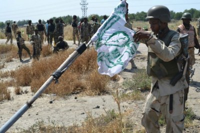 Boko Haram not yet defeated?  A Nigerian soldier pulls down a Boko Haram flag as a mark of victory (file photo).
