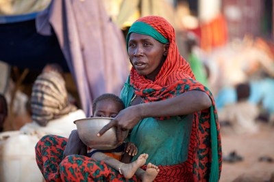 Une mère déplacée prépare de la nourriture pour son enfant près d’une base de la MINUAD à Um Baru, dans le Nord-Darfour.