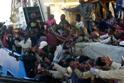 Over 400 migrants intercepted by the Misrata Coast Guard in four inflatable boats in April 2016 reach out for bottles of water being thrown from the shore. Many were later transferred to the Krareem Detention Centre.
