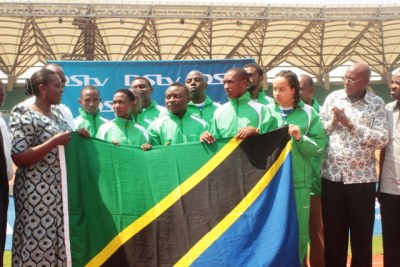 The Deputy Minister  Anastazia Wambura (left), hands over a Tanzanian flag to the Olympic team.