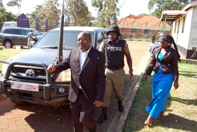 Under watch. King Mumbere escorted by a police officer on arrival at the Jinja Chief Magistrate’s Court.