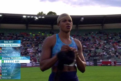 Blessing's wig falls off during long jump.