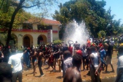 Protestors take bath using water from one of the pipes that were broken by vandals along Oginga-Odinga Street in Kisumu.