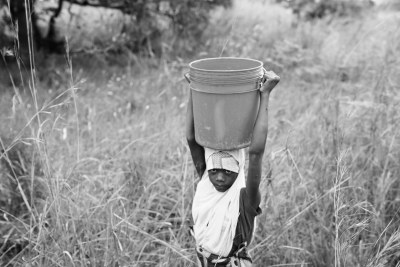 Ajida, 14, walks home after collecting water in Mococorene, Nampula province.