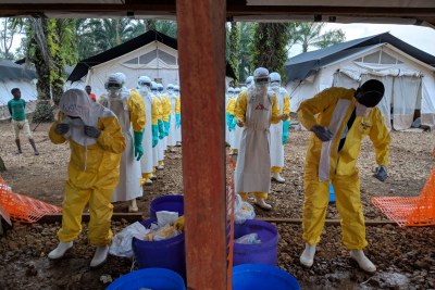 A team that has just finished setting up a tent in the high-risk zone in the Ebola treatment centre, getting out of their personal protective equipment (PPE). It’s hard work, and harder still in such attire. Photographer: Karin