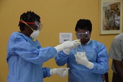 Health workers practice proper donning of protective gear during the training on vaccination against Ebola.