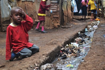A young boy sits over an open sewer in the Kibera slum, Nairobi. With up to one million residents, Kibera is Africa's largest slum and was the focal point for much of the post-election violence of 2007.
