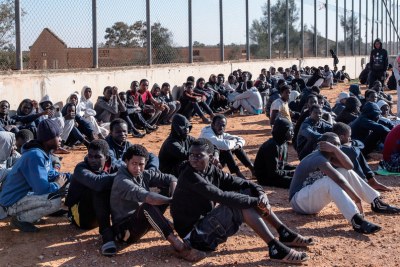 Des migrants sont assis dans la cour d'un centre de détention en Libye.