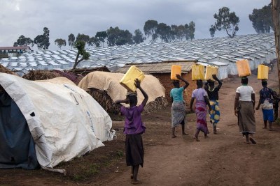 Des femmes portent de l'eau vers un camp de déplacés en RDC.