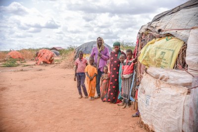 Borow Ali Khamis (third from left) and his family stand outside their makeshift shelter at the Dagahaley refugee camp. He was a farmer and livestock keeper in Somalia, but has lost everything due to the long drought. Dadaab, Kenya, June 2022.